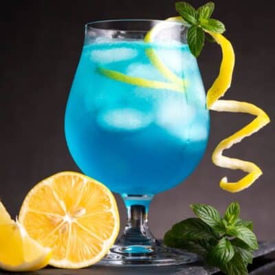 最好的蓝色泻湖鸡尾酒饮料配方配有柠檬扭曲和罗勒装饰。